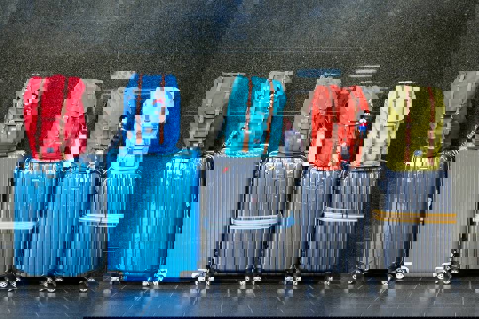 Row of suitcases with backpacks on top